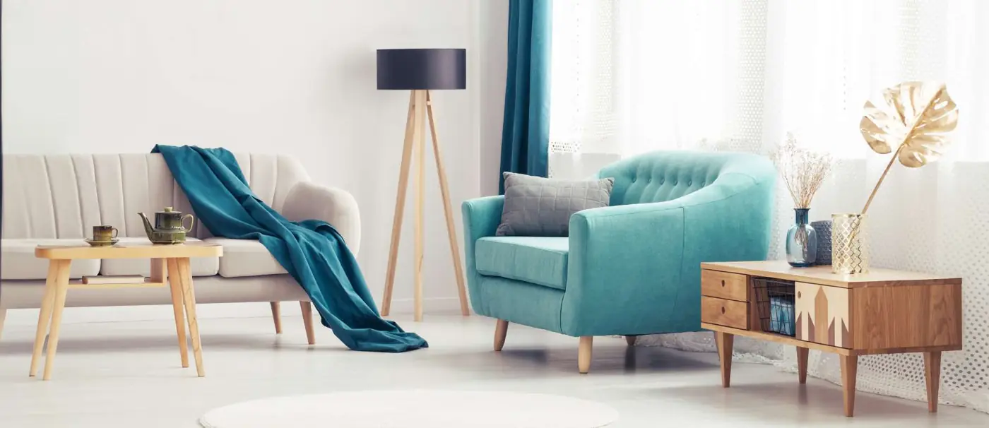 Living luminoso con sillones claros y un sillón turquesa